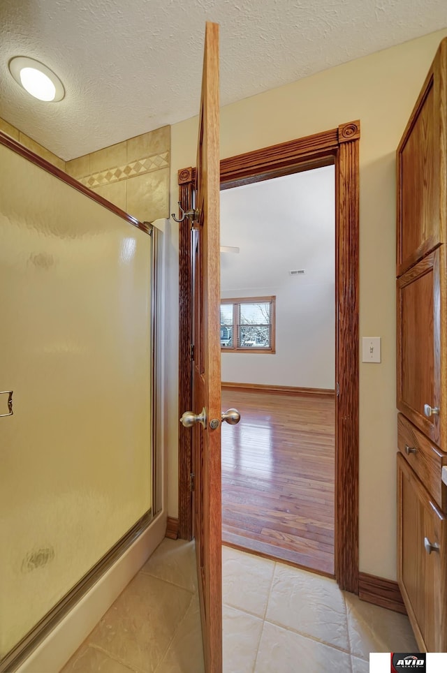 bathroom with a stall shower, a textured ceiling, and tile patterned floors