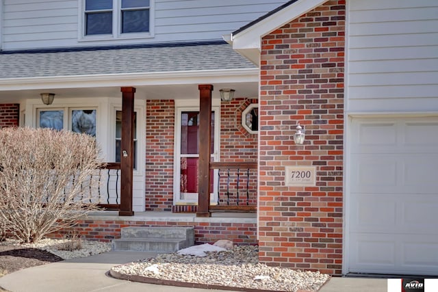 entrance to property with a garage, brick siding, a porch, and roof with shingles