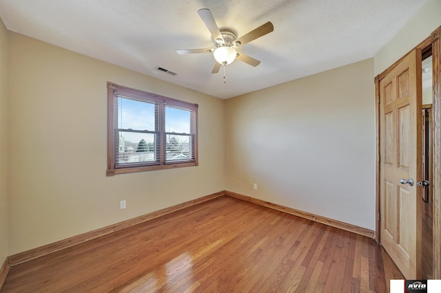 unfurnished bedroom with a textured ceiling, ceiling fan, light wood-style flooring, visible vents, and baseboards