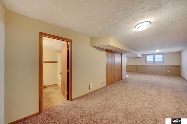 bonus room with a textured ceiling, baseboards, visible vents, and light colored carpet