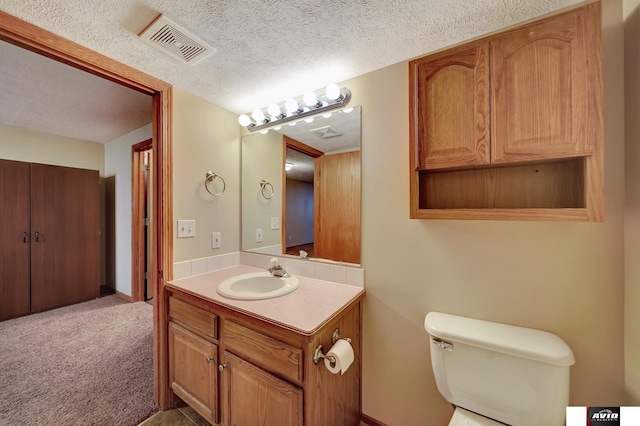 bathroom with visible vents, toilet, vanity, and a textured ceiling