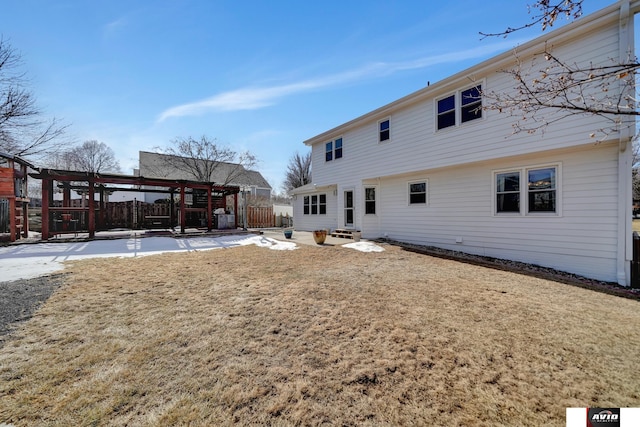 rear view of house with entry steps, a yard, and fence