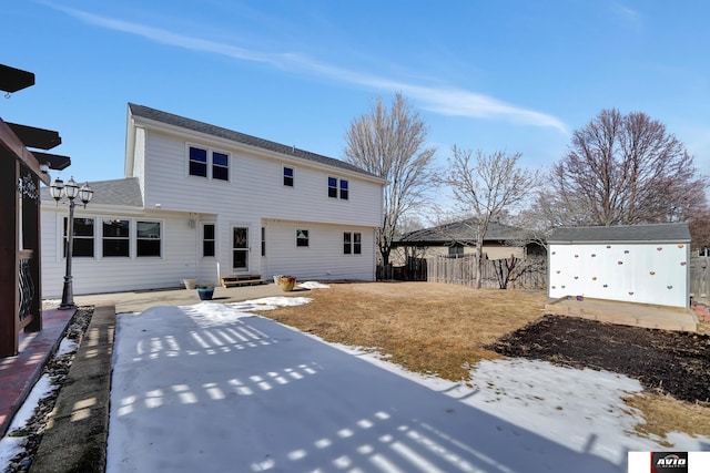 back of property featuring entry steps, fence, an outdoor structure, and a patio