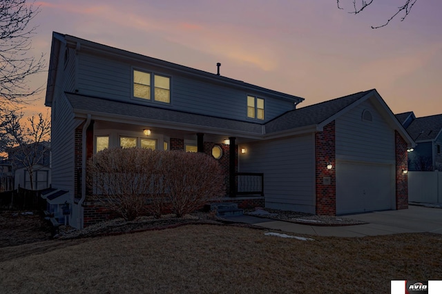 traditional home featuring a garage, brick siding, and driveway