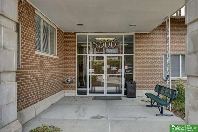 property entrance with a patio area, brick siding, and visible vents