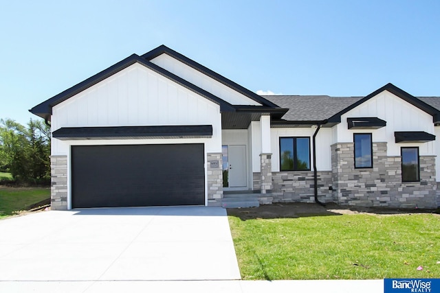 modern farmhouse style home with concrete driveway, stone siding, an attached garage, a front lawn, and board and batten siding