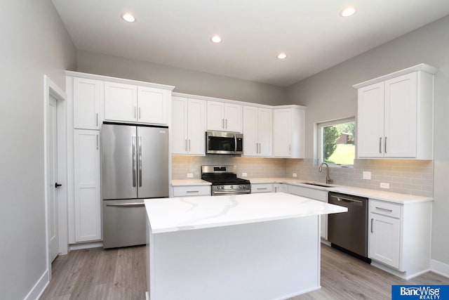 kitchen featuring appliances with stainless steel finishes, a center island, white cabinets, and light wood finished floors