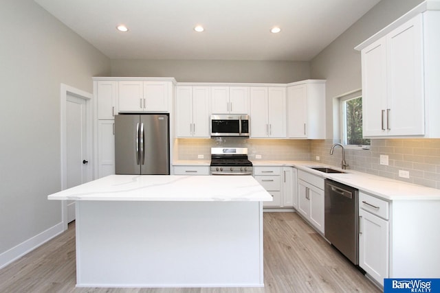 kitchen featuring appliances with stainless steel finishes, a sink, white cabinetry, and a center island