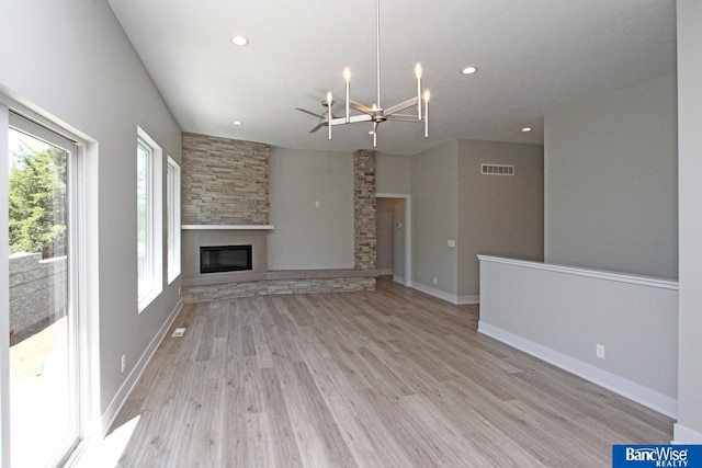 unfurnished living room featuring a notable chandelier, recessed lighting, visible vents, light wood-type flooring, and a glass covered fireplace