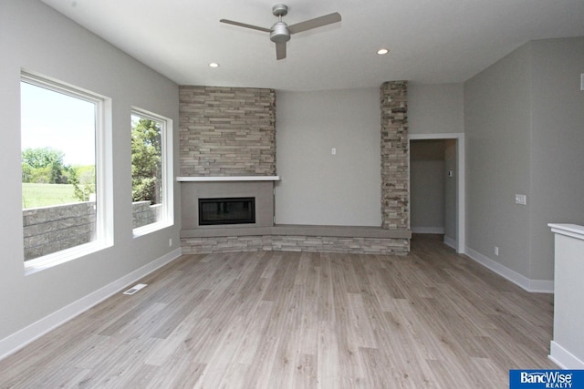 unfurnished living room with visible vents, baseboards, a glass covered fireplace, light wood-type flooring, and recessed lighting