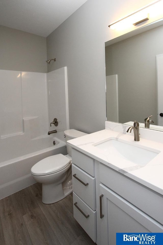 bathroom featuring toilet, tub / shower combination, wood finished floors, and vanity