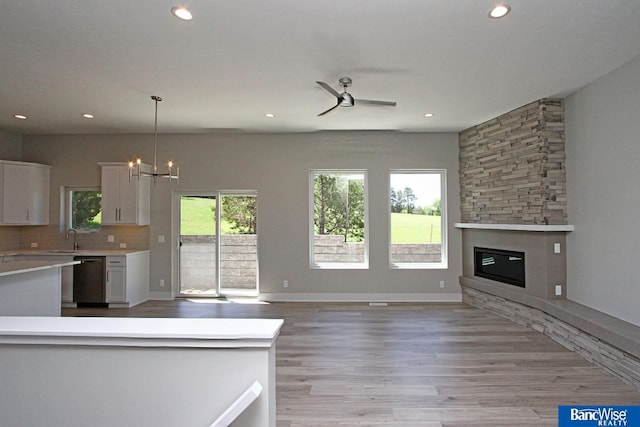 kitchen featuring dishwashing machine, white cabinets, open floor plan, light countertops, and decorative light fixtures