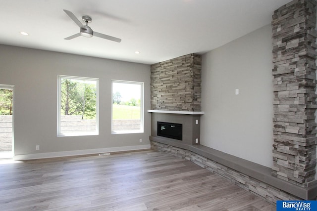 unfurnished living room with a healthy amount of sunlight, light wood-style floors, ceiling fan, and a fireplace