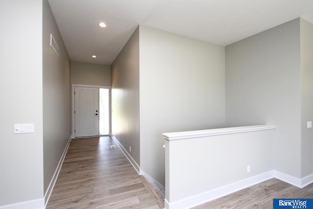 hallway featuring light wood finished floors, recessed lighting, visible vents, and baseboards