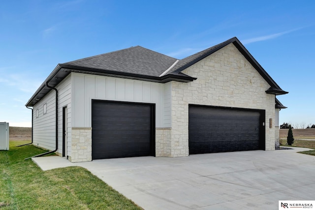 exterior space with a garage, roof with shingles, board and batten siding, and concrete driveway