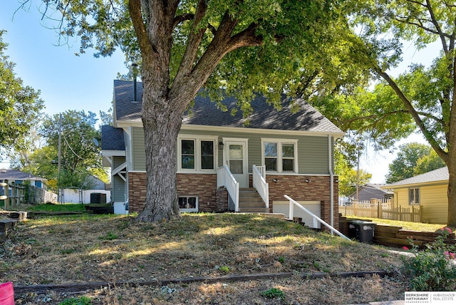 view of front of house with entry steps, a shingled roof, and fence