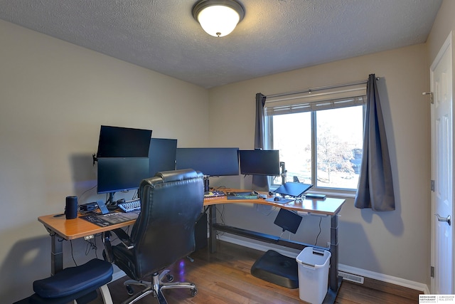 office area featuring wood finished floors, visible vents, and a textured ceiling