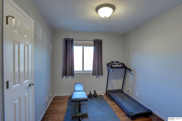 workout area featuring a textured ceiling, baseboards, and wood finished floors