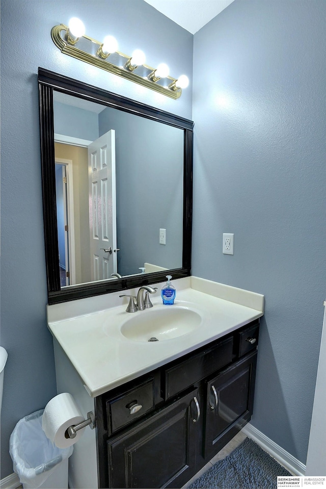 bathroom with toilet, vanity, and baseboards