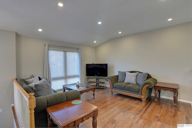 living room featuring lofted ceiling, light wood-style flooring, recessed lighting, and baseboards