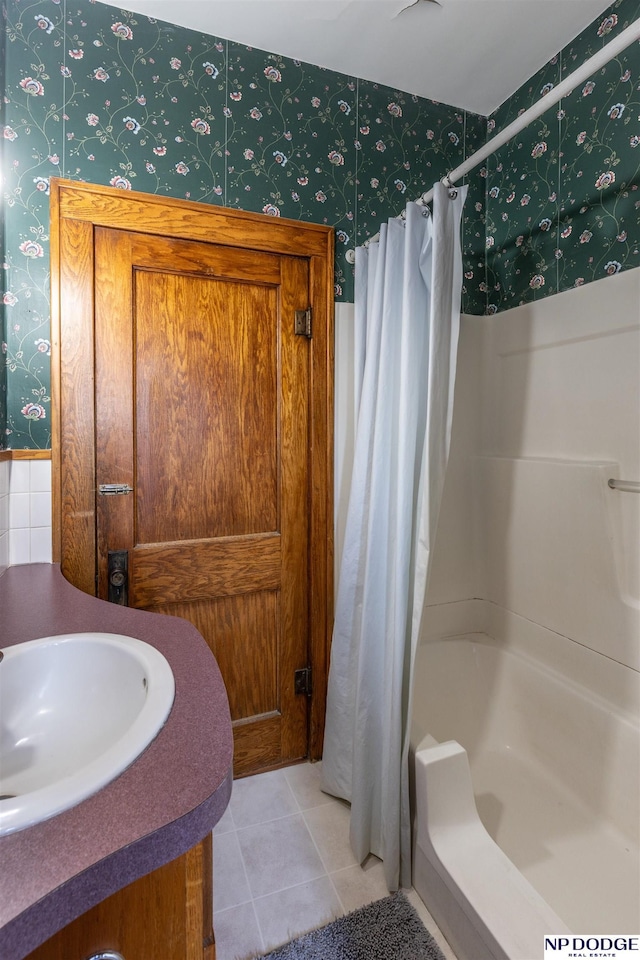 bathroom with tile patterned floors, a sink, shower / bath combo with shower curtain, and wallpapered walls