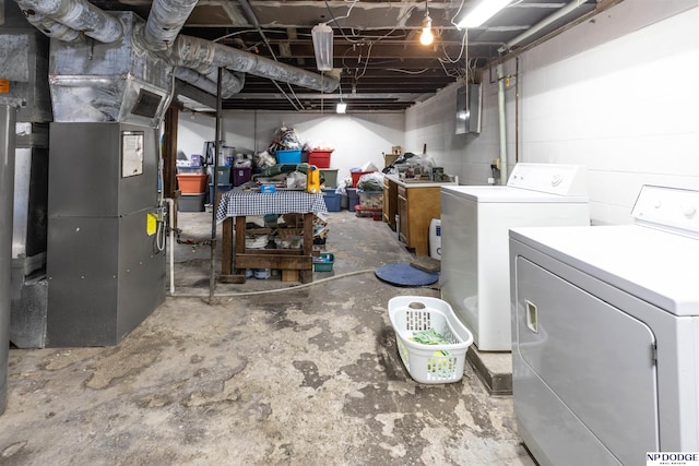 unfinished below grade area featuring washing machine and clothes dryer, concrete block wall, and heating unit