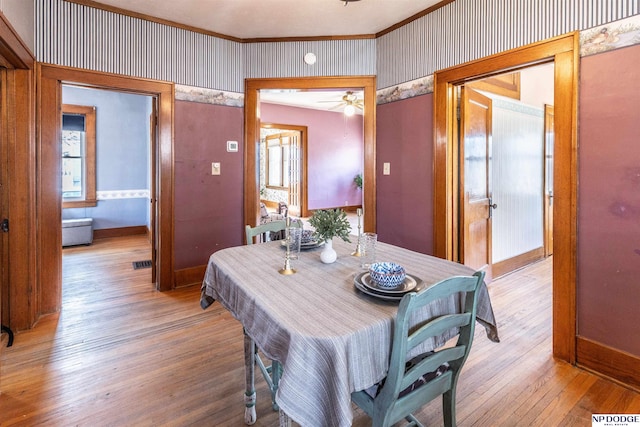 dining area with hardwood / wood-style flooring, visible vents, baseboards, and wallpapered walls