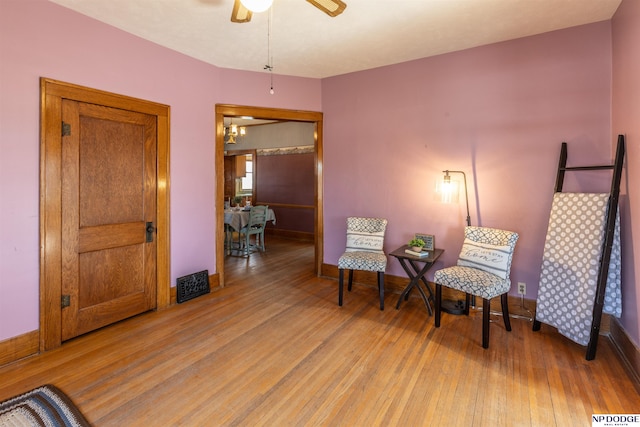 sitting room featuring a ceiling fan, wood finished floors, visible vents, and baseboards