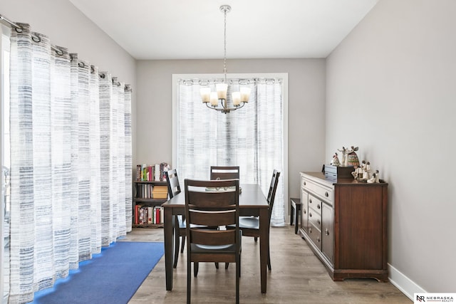 dining space with a chandelier, light wood-type flooring, and baseboards