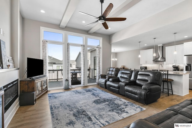 living room featuring ceiling fan with notable chandelier, wood finished floors, beam ceiling, and recessed lighting