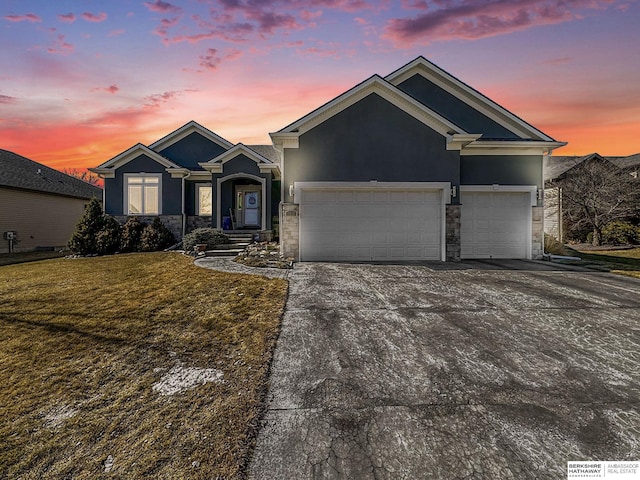 view of front of house with stucco siding, an attached garage, stone siding, driveway, and a front lawn