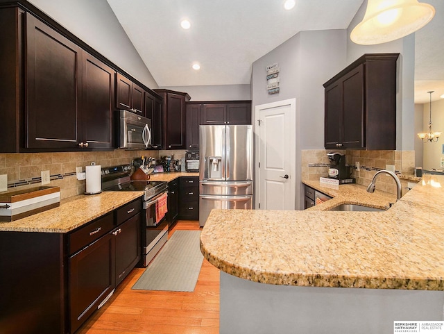 kitchen featuring appliances with stainless steel finishes, hanging light fixtures, a peninsula, and a sink