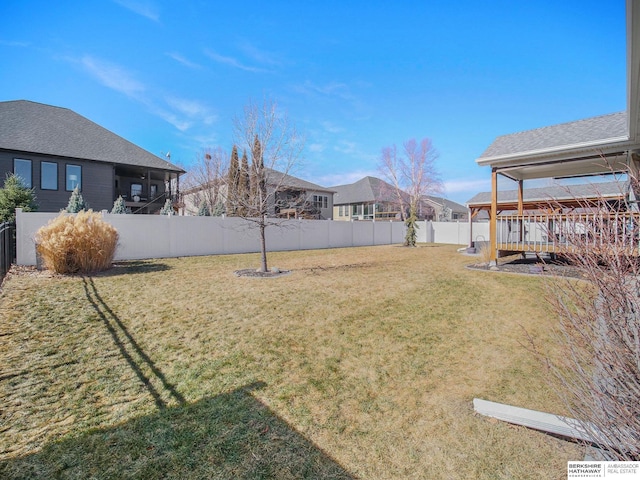 view of yard with a residential view, a fenced backyard, and a wooden deck