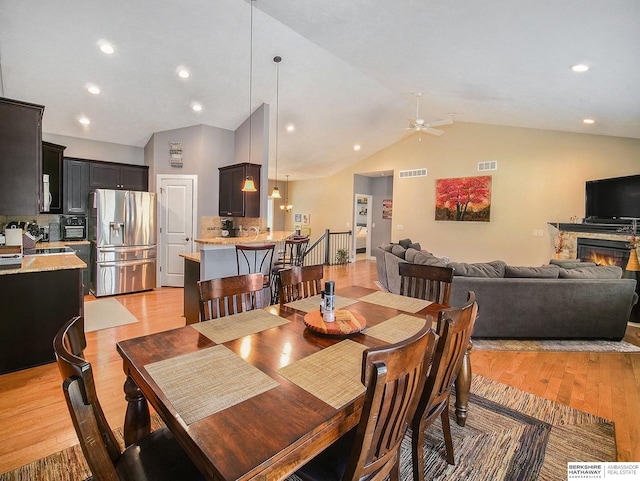 dining area featuring light wood-style flooring, recessed lighting, visible vents, a ceiling fan, and a glass covered fireplace