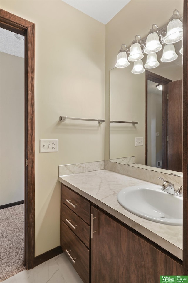 bathroom with marble finish floor, vanity, and baseboards