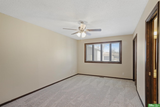 unfurnished bedroom with light colored carpet, ceiling fan, a textured ceiling, and baseboards