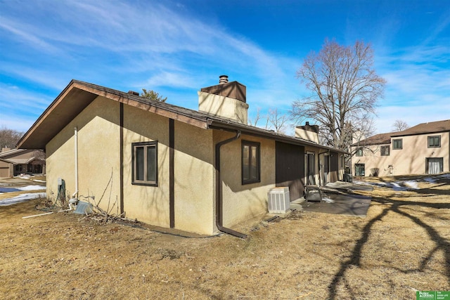 view of property exterior with a chimney and stucco siding