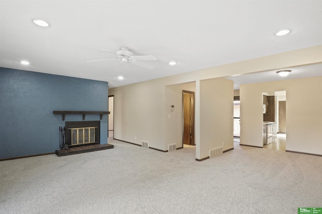 unfurnished living room featuring recessed lighting, visible vents, light colored carpet, and a glass covered fireplace