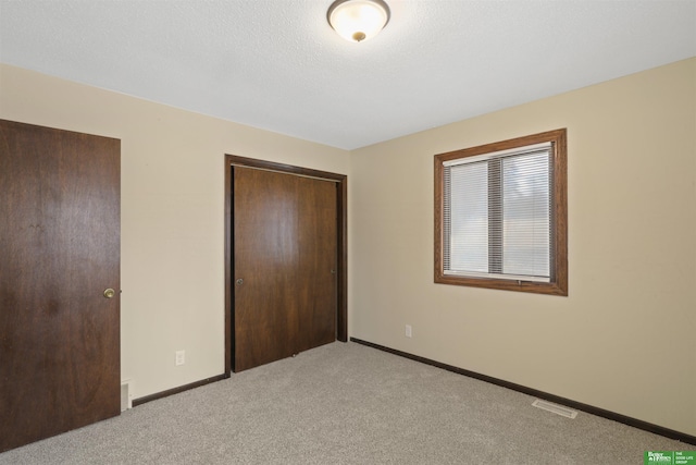 unfurnished bedroom featuring baseboards, visible vents, a closet, and light colored carpet