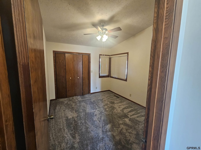 unfurnished bedroom with baseboards, ceiling fan, a textured ceiling, carpet floors, and a closet