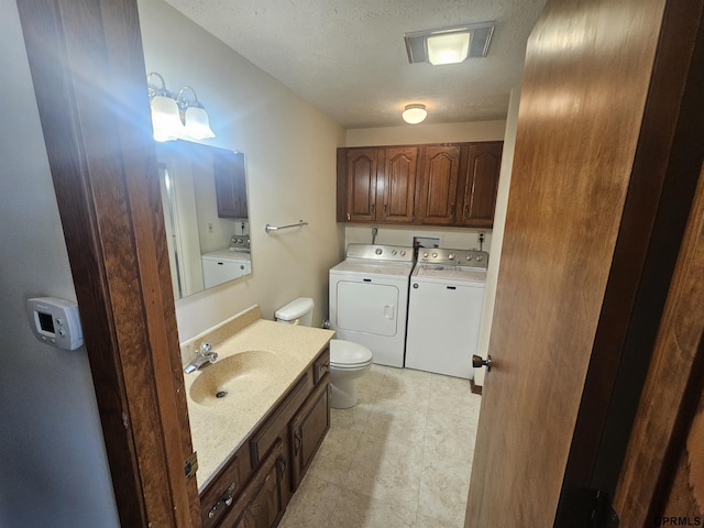 bathroom with washer and clothes dryer, visible vents, toilet, a sink, and a textured ceiling