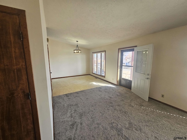 unfurnished room featuring a textured ceiling, carpet flooring, and baseboards