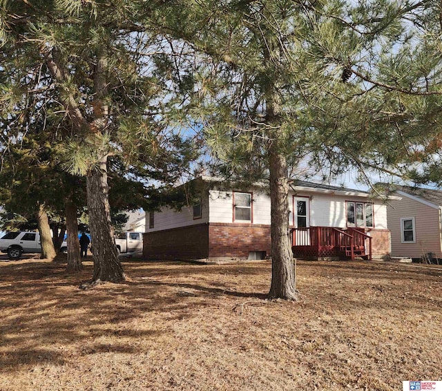 view of property exterior with a wooden deck, a lawn, and brick siding