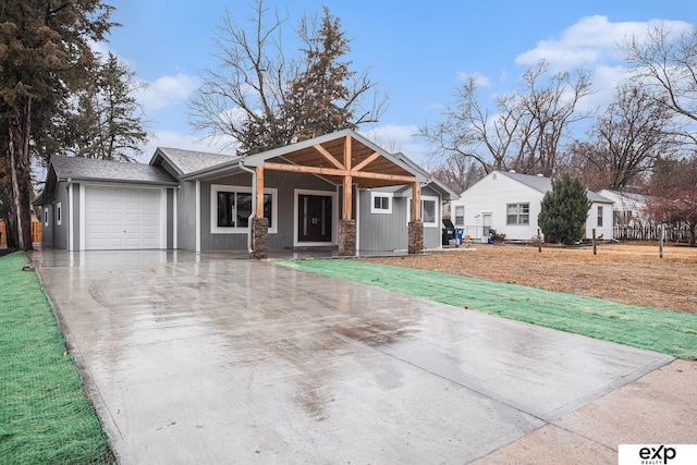 view of front of house with a garage, concrete driveway, and a shingled roof