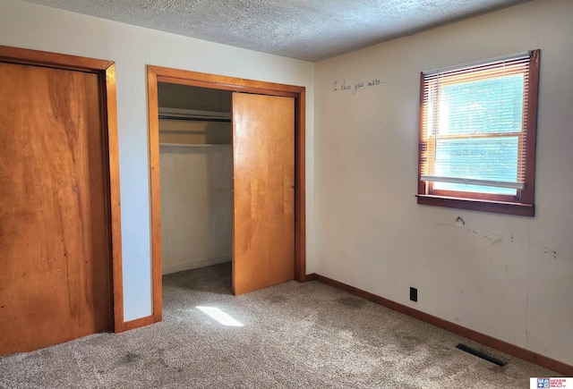 unfurnished bedroom with baseboards, visible vents, a textured ceiling, carpet floors, and a closet