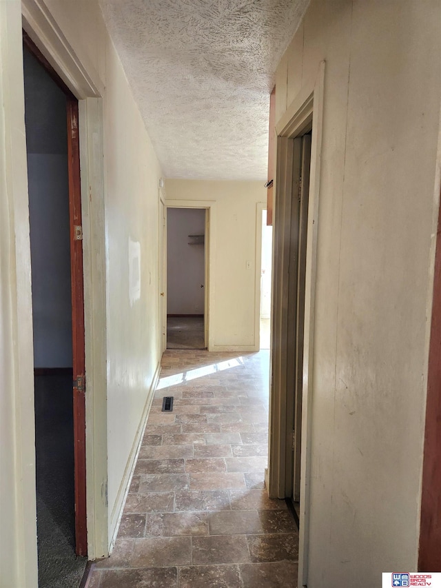 hallway with a textured ceiling and visible vents