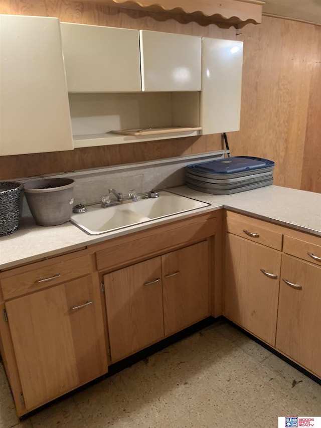 kitchen featuring light countertops, a sink, wooden walls, and light floors