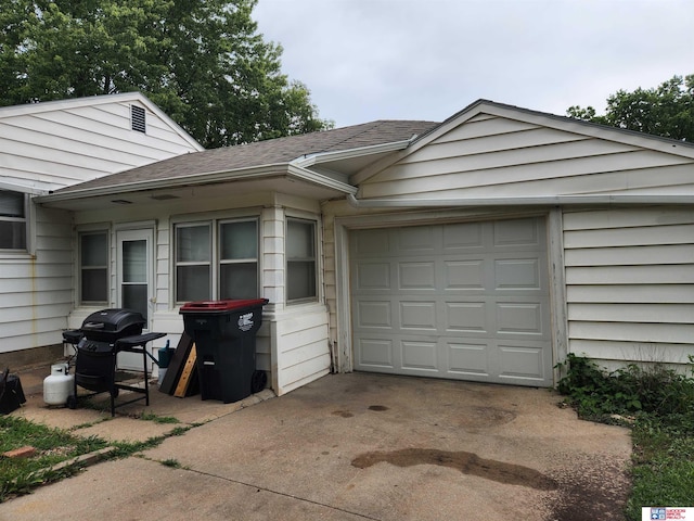 view of side of home featuring driveway, a shingled roof, and a garage