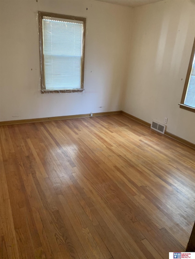 spare room featuring light wood finished floors, baseboards, and visible vents