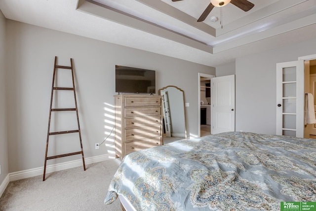 bedroom featuring a raised ceiling, baseboards, and light carpet